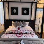 Luxurious honeymoon suite with rose petals on the bed, overlooking a tranquil pool.