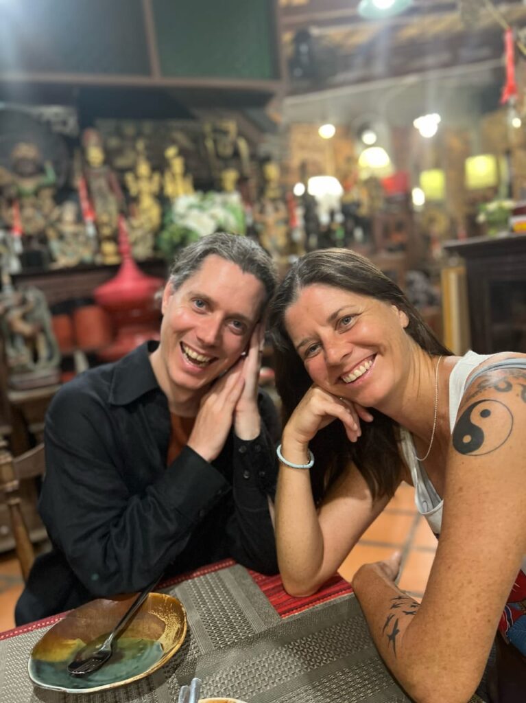 Kirsten Hickey and her brother Dane smiling together at a table in a warmly lit restaurant with artistic decor.